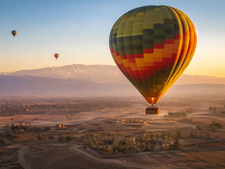 Hot air balloon over Marrakech countryside at sunrise with Atlas Mountains
